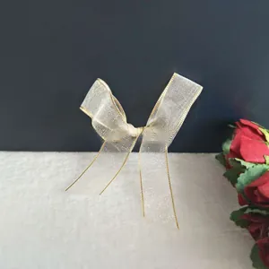 Detailed close-up of handmade cream organza bow hair clip with gold wire edges