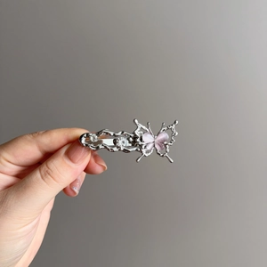 Détail d'une pince à cheveux papillon en argent avec œil de chat rose et strass