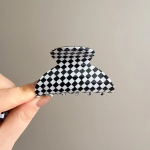 Detail view of large black and white checkered hair claw clip with glossy finish