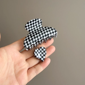 Detail view of black and white checkerboard hair claw set with heart shape accessory