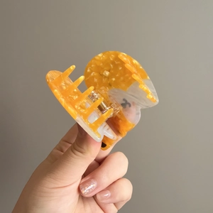Cellulose acetate corgi dog hair claw clip in tortoiseshell orange held in hand