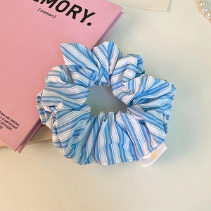 Detailed macro view of the blue and white striped fabric scrunchie with heart label