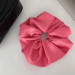 Detailed view of fuchsia satin scrunchie with high sheen and premium pleated texture