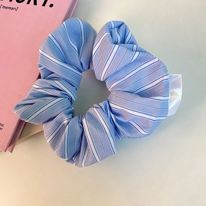 Minimalist blue and white striped fabric scrunchie with a small heart satin label