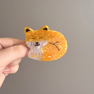 Close-up of orange marble acetate fox hair claw clip held by hand for size scale