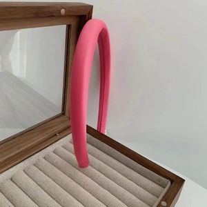 Detail of a thick magenta padded headband displayed inside a wooden jewelry box