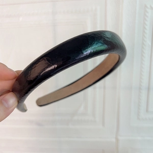 Détail d'un serre-tête en cuir PU noir brillant avec texture martelée et doublure antidérapante