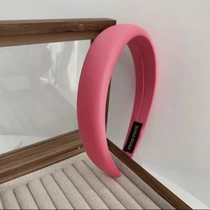 Detailed view of a handmade pink padded headband resting on a luxury jewelry box