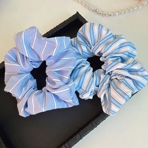 Detail of two striped scrunchies in blue and violet on a black leather tray decor