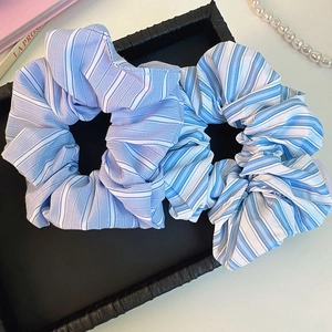 Detailed view of two blue and white striped scrunchies in a black leather tray