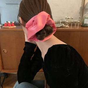 Pink satin scrunchie hair tie with elegant silk texture for high ponytail styling