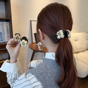 Dettaglio di fermagli per capelli a fiore in maglia nei toni crema e kaki sui capelli