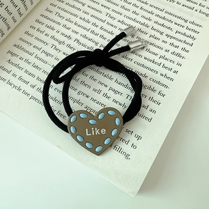 Minimalistisches Haargummi mit Herzanhänger Like auf einem Buchhintergrund