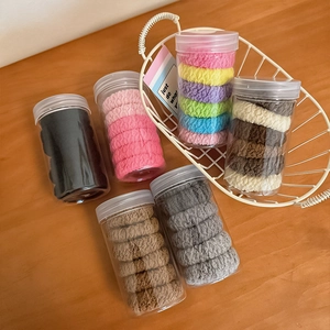 Thick elastic hair ties set in clear jars with various colors on wooden desk background