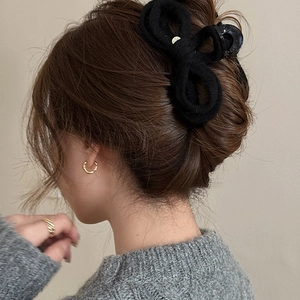 Knitted black bow hair claw clip styled on a woman's bun for an elegant winter look