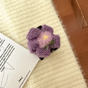 Dettaglio di un fermaglio per capelli a fiore viola in maglia con foglia verde