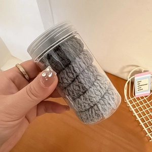 Close-up of grey gradient elastic hair ties set in a portable transparent bottle