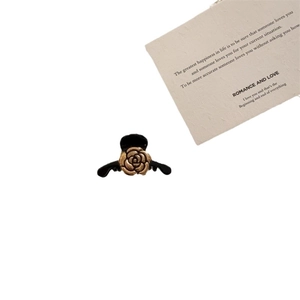 Elegant small black claw clip with golden embossed rose design on white background