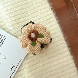 Dettaglio della molletta per capelli a fiore lavorata a maglia con petali color caffè