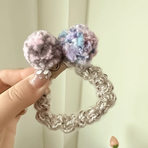 Vue détaillée des boules en peluche et de la texture tissée sur l'élastique à cheveux