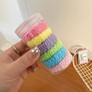 Close-up of colorful macaron-colored elastic hair ties in a transparent storage jar