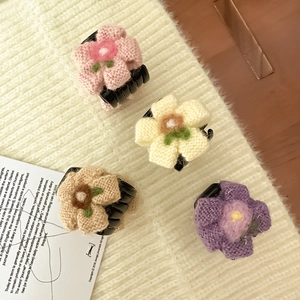 Dettaglio macro di fermagli per capelli a fiori in maglia rosa, giallo e beige