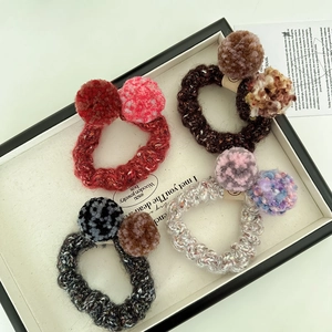 Vue détaillée de quatre chouchous tricotés avec pompons en peluche aux couleurs d'automne