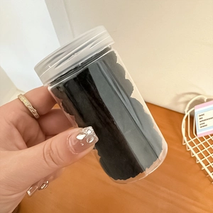 Close-up of hair ties in a clear cylindrical plastic jar with a translucent white lid