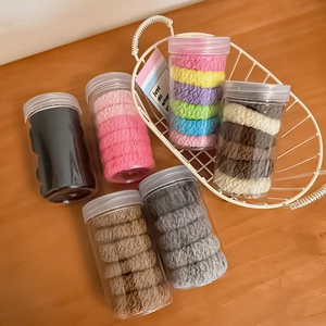 Detail of multi-colored high-elastic hair ties set in a transparent storage bottle