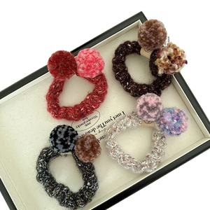 Lot de quatre chouchous tricotés avec pompons en peluche aux couleurs automnales sur plateau