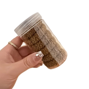 Thick brown hair scrunchies set in a clear cylindrical jar with a silver screw lid