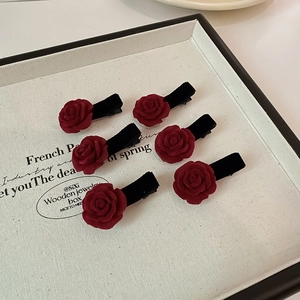 Détail de six pinces à cheveux fleurs de camélia en velours bordeaux sur un plateau