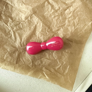Détail d'une barrette noeud en acétate rose brillant avec inscription française