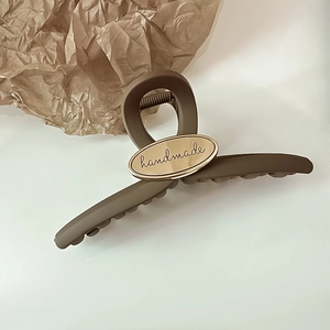Close-up of matte brown hair claw with golden handmade engraving on the metal plate