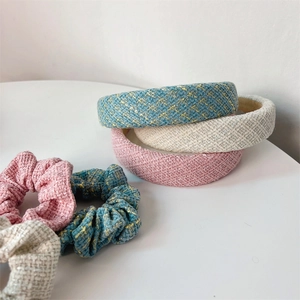 Dettaglio di elastici e cerchietti in tweed nei colori azzurro cielo, rosa e bianco crema