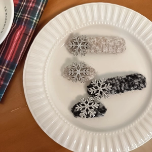 Close-up of four tweed snowflake hair clips with rhinestones on a white ceramic plate
