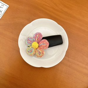 Dettaglio del fermaglio per capelli a fiori colorati con base in pelle su vassoio bianco