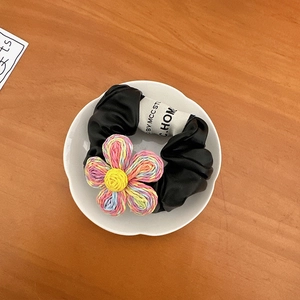 Dettaglio di elastico per capelli in finta pelle nera con fiore intrecciato colorato