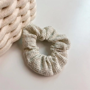 Elastico per capelli in tessuto tweed beige e grigio su sfondo bianco pulito