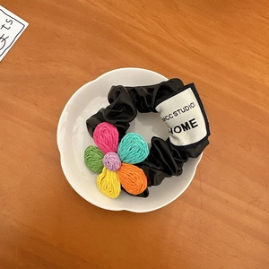 Dettaglio dell'elastico in seta nera con fiori lavorati a maglia su un piatto bianco