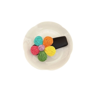 Fermaglio per capelli a fiore intrecciato colorato con cinque petali su un piatto