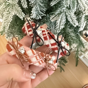 Detail of tweed plaid hair clips with leather bows and heart crystals in hand