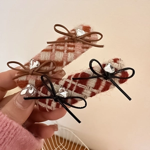 Detail of tweed checkered bow hair clip with heart rhinestone and woven texture