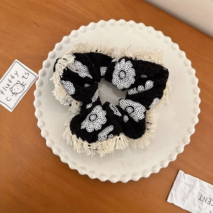Détail d'un chouchou vintage avec imprimé floral blanc et bordure à franges douces