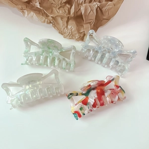 Detailed view of four acetate hair claw clips with elegant marble patterns and metal springs