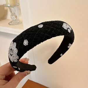 Détail d'un serre-tête rembourré en tweed noir avec broderies florales de paillettes