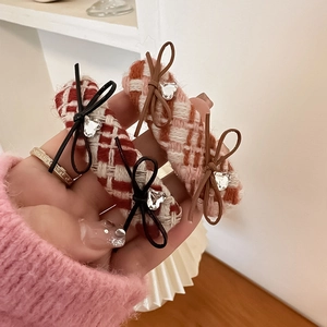 Detailed close-up of plaid fabric hair clips with leather bows and heart crystals
