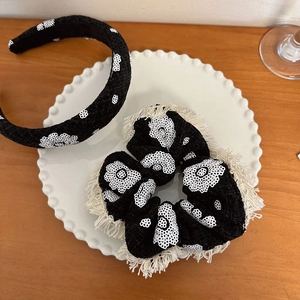 Ensemble serre-tête et chouchou en tweed noir à fleurs sur plateau blanc