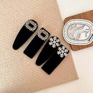 Detail of four black velvet hair clips with sparkling rhinestone snowflakes and square buckles