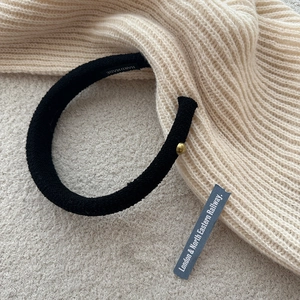 Detail of handmade black tweed headband with gold bead and textured fabric finish